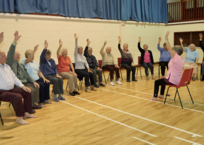 Group of older people taking part in exercise class at landford village hall